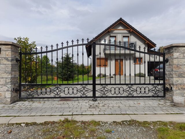 Brama ogrodzeniowa wjazdowa uchylna kuta z&nbsp;podłużnych prętów&nbsp;BU 098