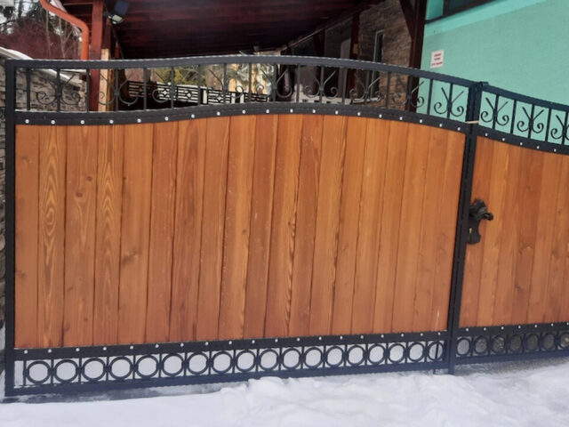 Brama wjazdowa, dwuskrzydłowa, uchylna, kuta z&nbsp;drewnem BU 104